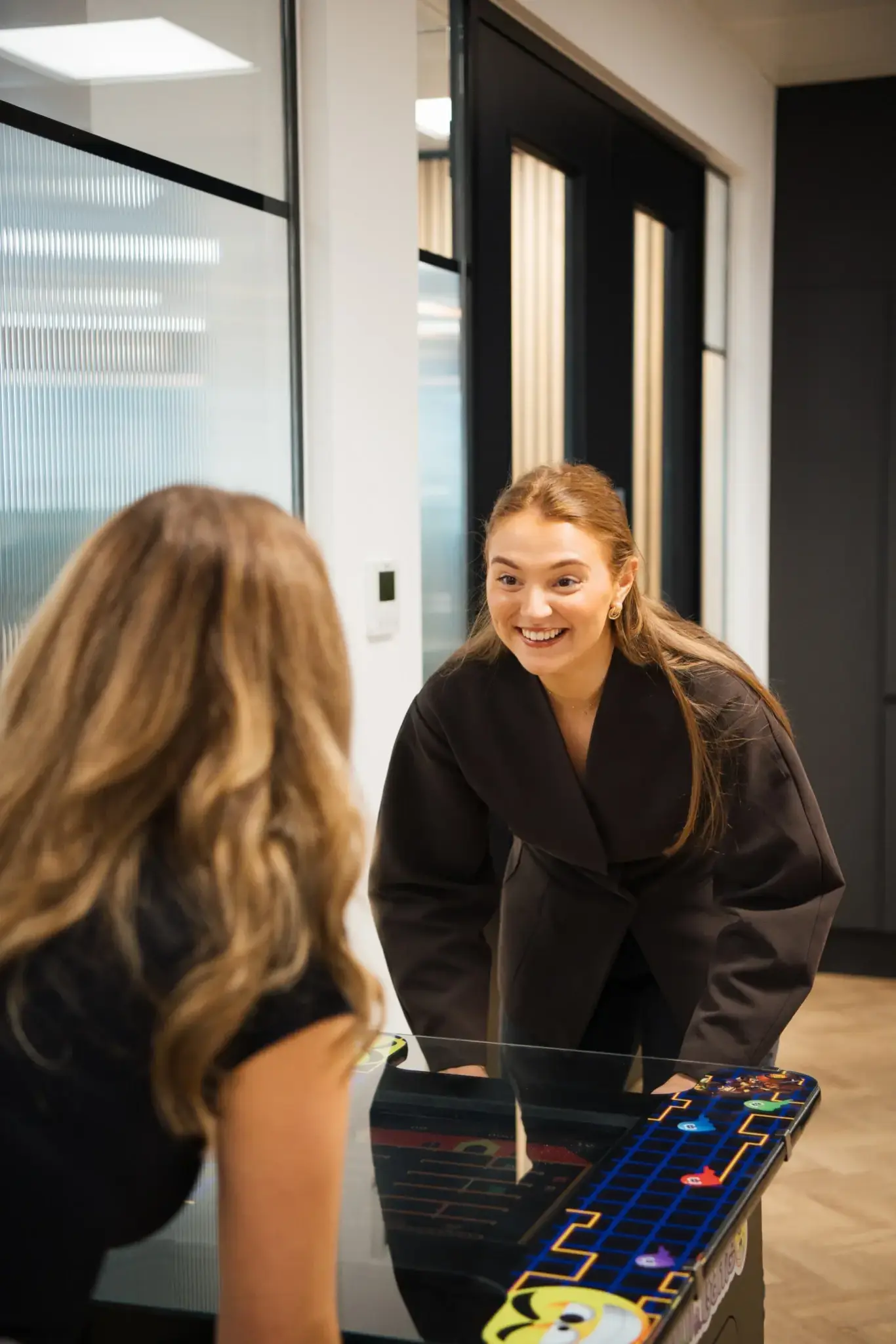 IDHL employees smiling whilst playing an arcade game