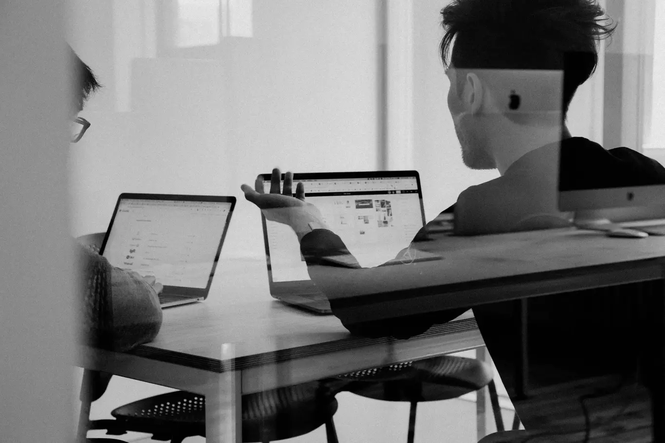 Image of two men with laptops talking