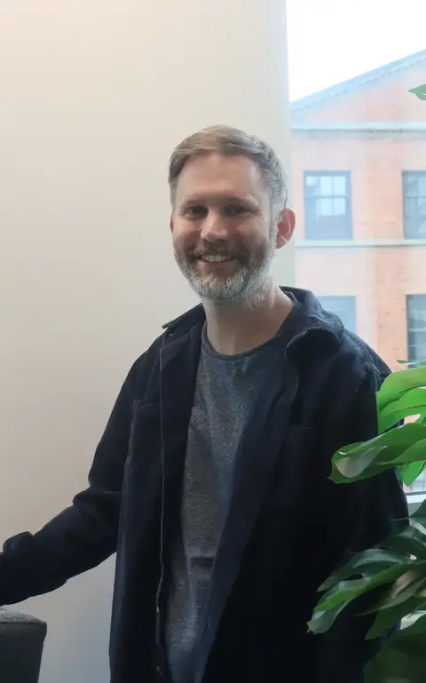 a man standing next to a plant