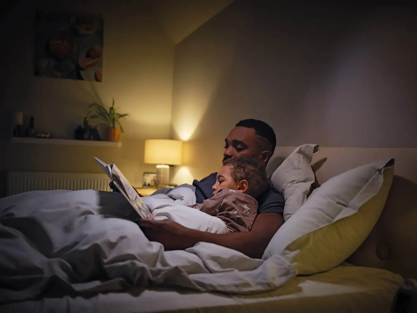a man reading a book to a baby in bed
