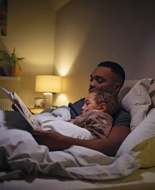 a man reading a book to a baby in bed