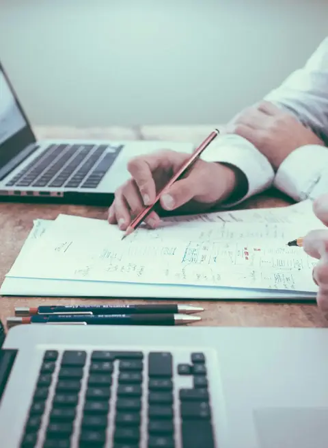 a man holding a pen and writing on a piece of paper