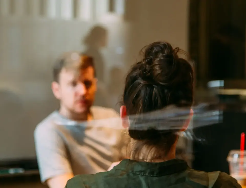 a woman sitting at a table with a man behind her