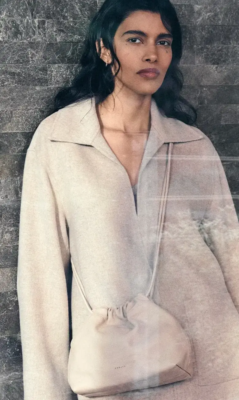 a woman standing against a brick wall