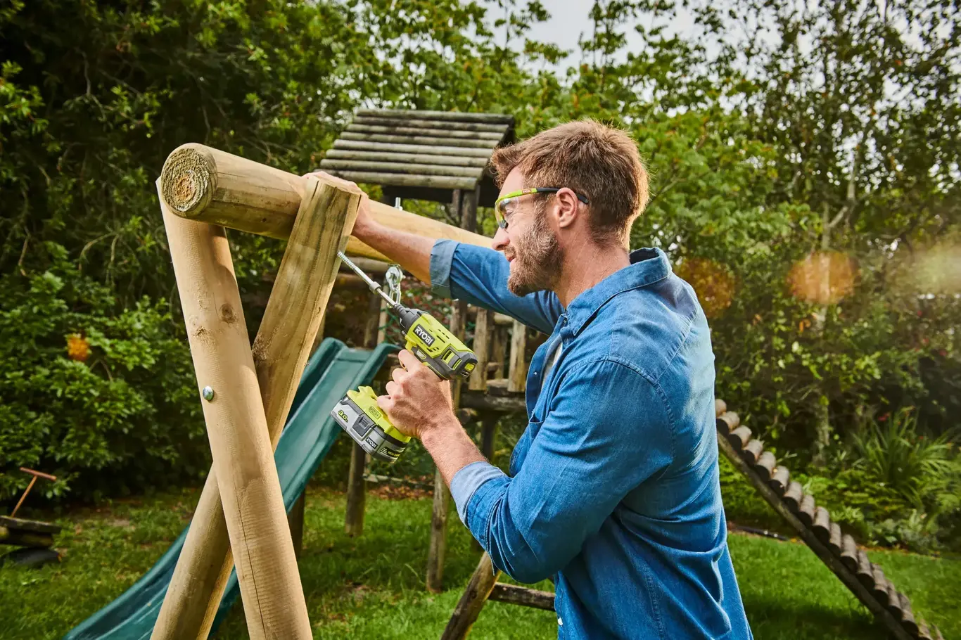 a man holding a drill and a swing set