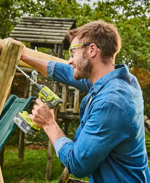 a man holding a drill and a swing set