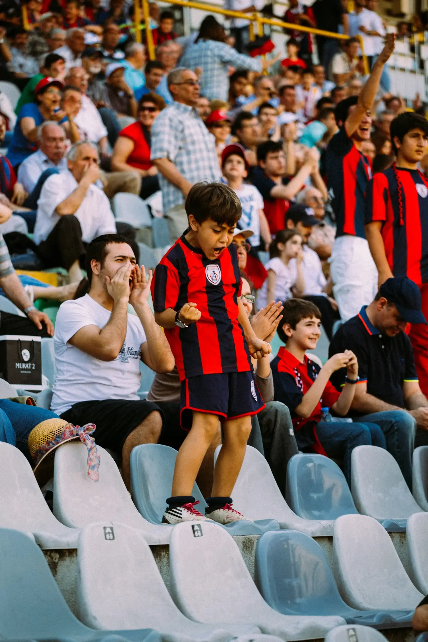 a boy standing on a chair in a stadium