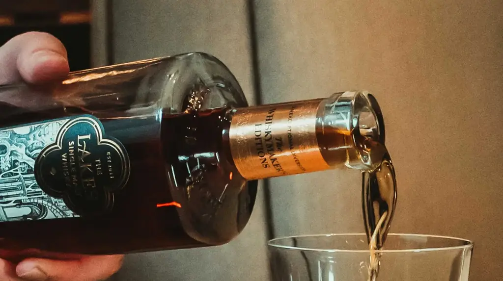 a person pouring a glass of alcohol into a glass