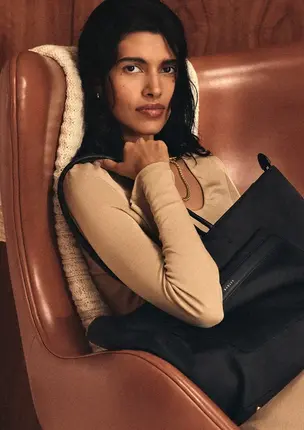 a woman sitting in a chair holding a purse