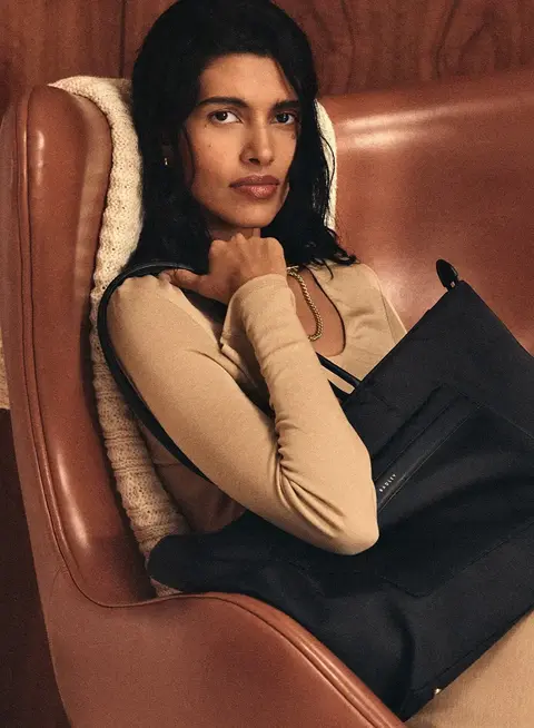 a woman sitting in a chair holding a purse