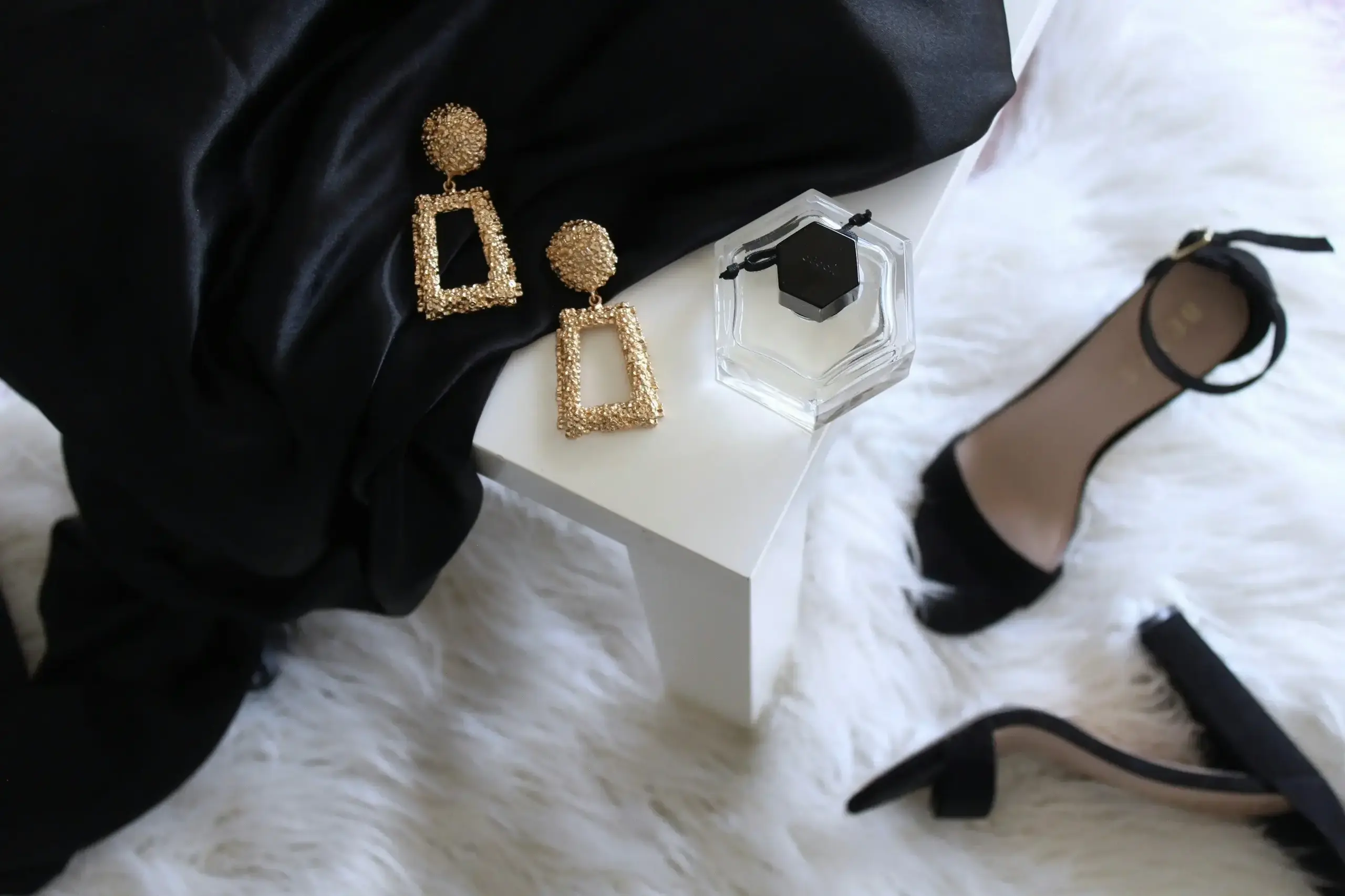 a pair of gold earrings on a white table