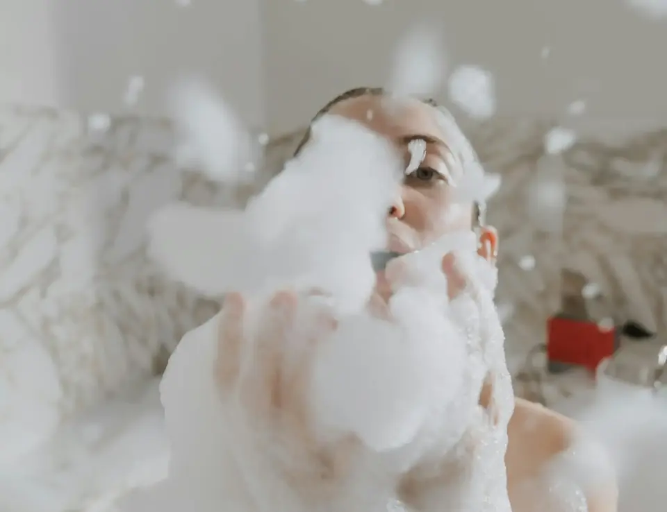 a woman in a bathtub blowing bubbles