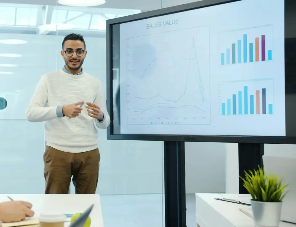 Professional presenting financial review on a screen displaying bar graphs