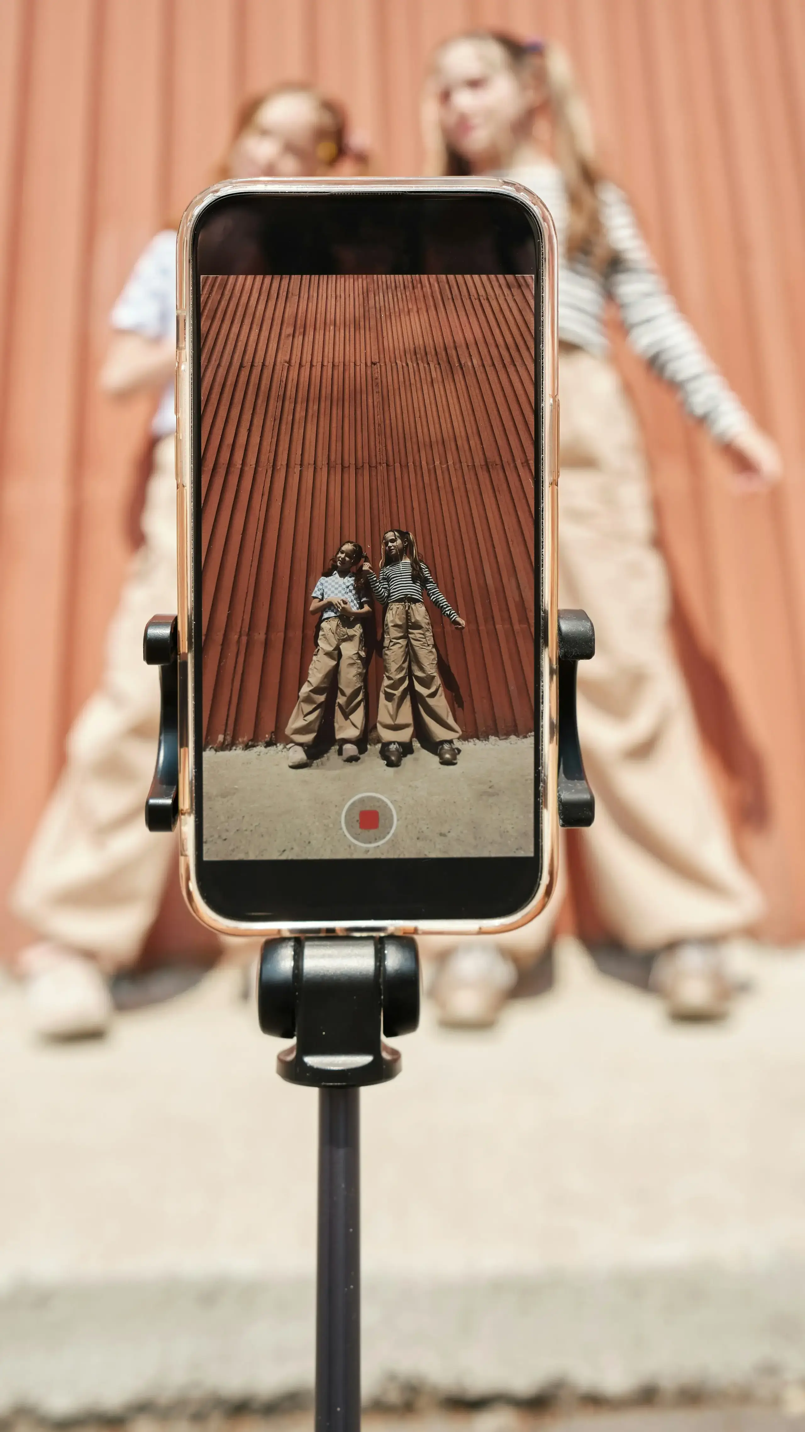 Two girls filming themselves posing with a phone on a tripod