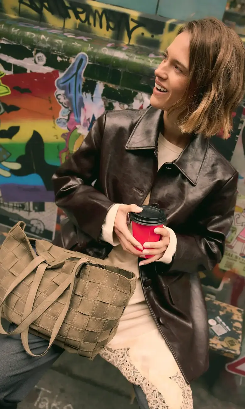 a woman holding a cup and a purse
