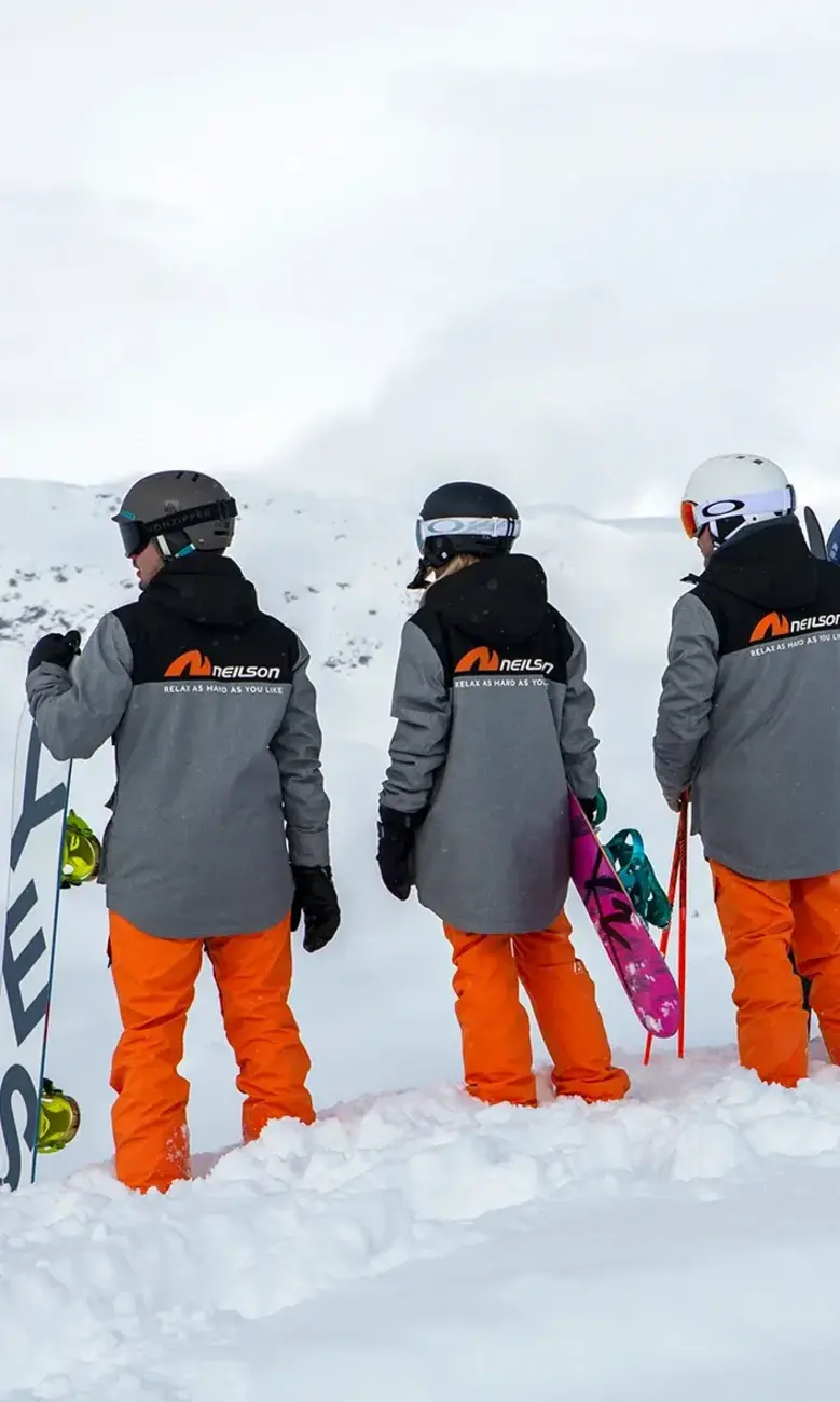 Three Neilson ski instructors stood on a snowy mountain