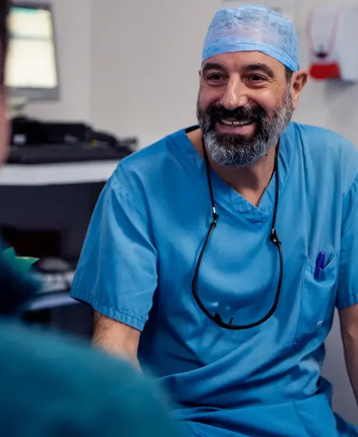 Doctor in blue scrubs sitting down and smiling