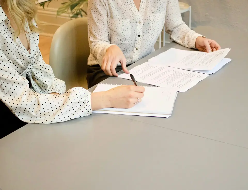 A woman sitting at a table with papers and a pen