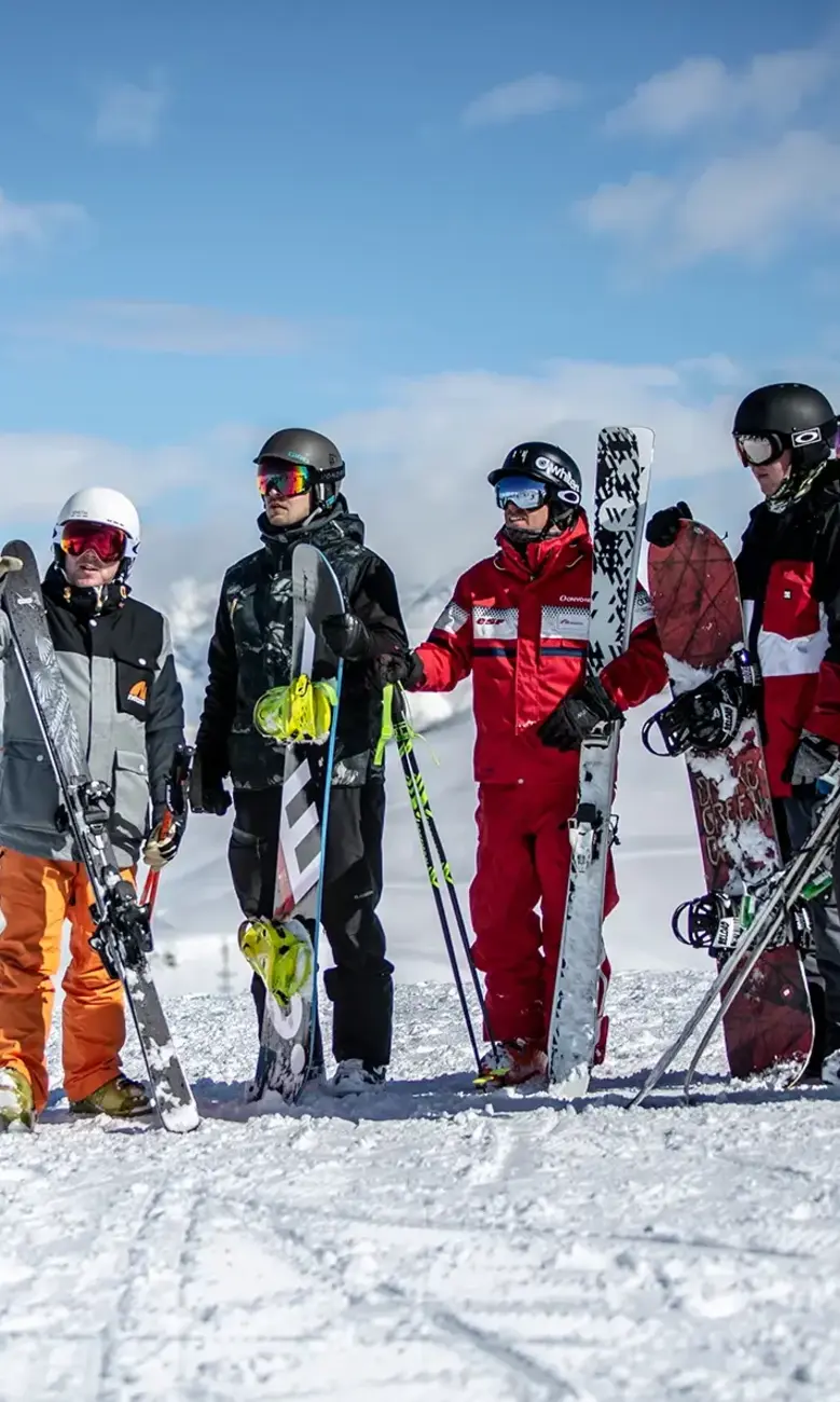 Group of skiers and snowboarders stood on a snowy mountain