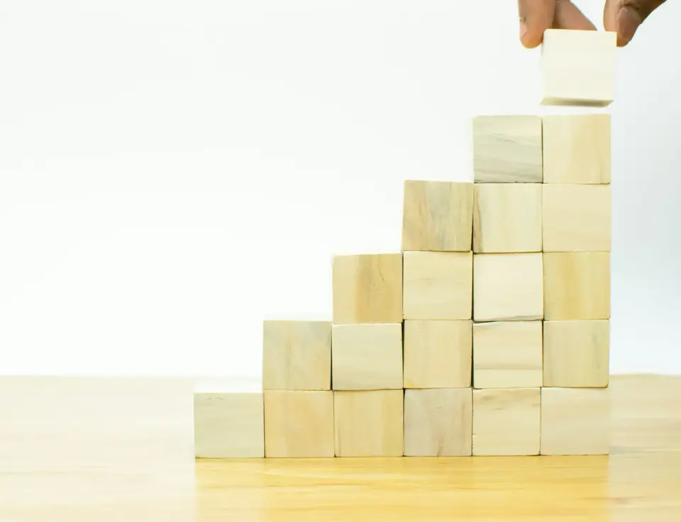 a hand placing a block on top of a stair