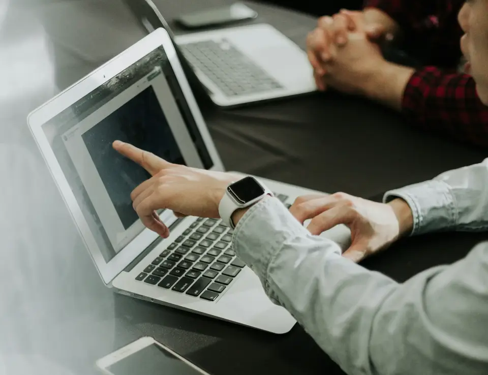 a person pointing at a laptop