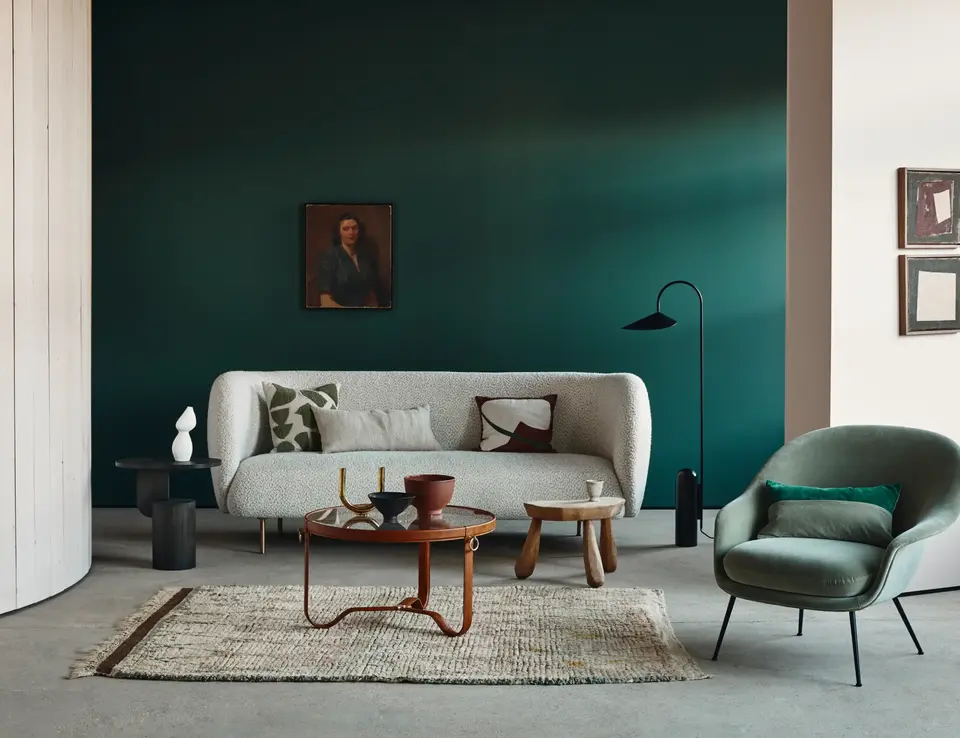 Craig & Rose green paint displayed in a living room styled with a white sofa and wooden furnishings.
