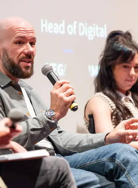 a man holding a microphone in front of a man sitting in a chair