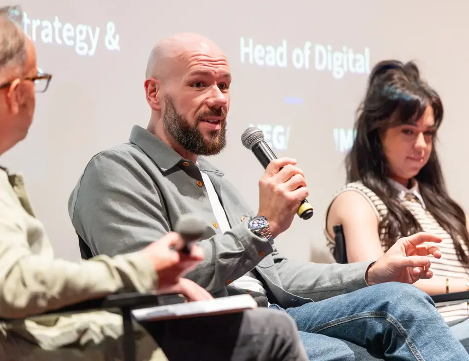 a man holding a microphone in front of a man sitting in a chair