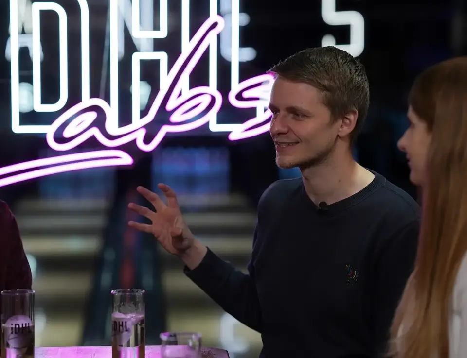 People talking in front of IDHL Labs neon sign