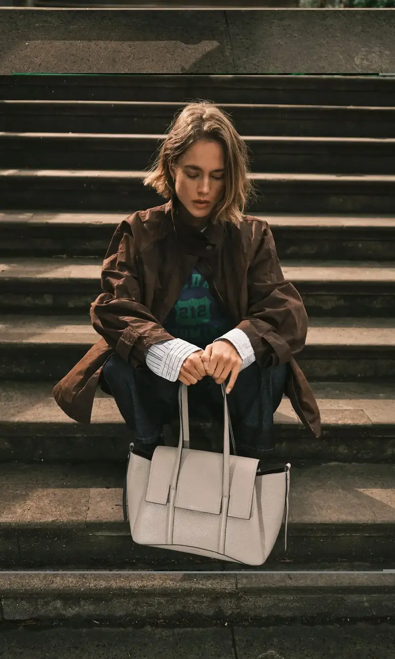 a woman sitting on steps with a white purse