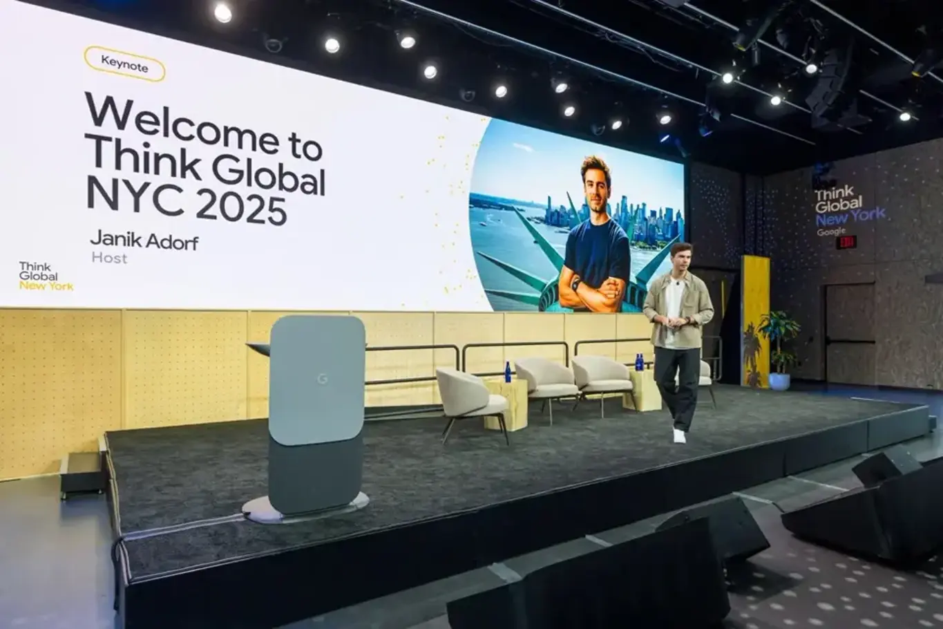 a man standing on a stage with a large screen
