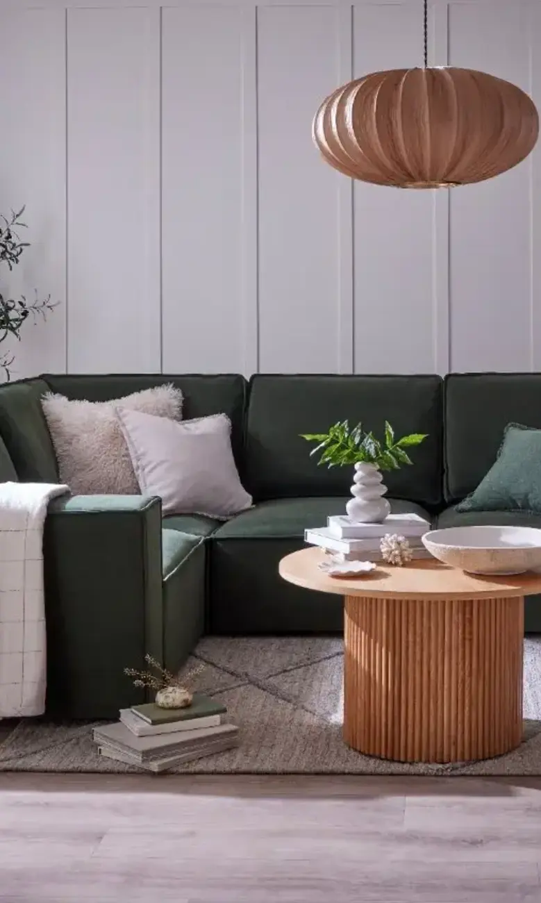 a living room with a green couch and a round coffee table