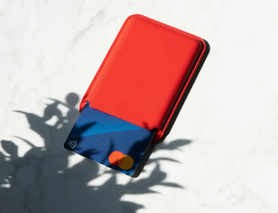 Credit card in a card holder with a shadow of a plant falling on its bottom left corner