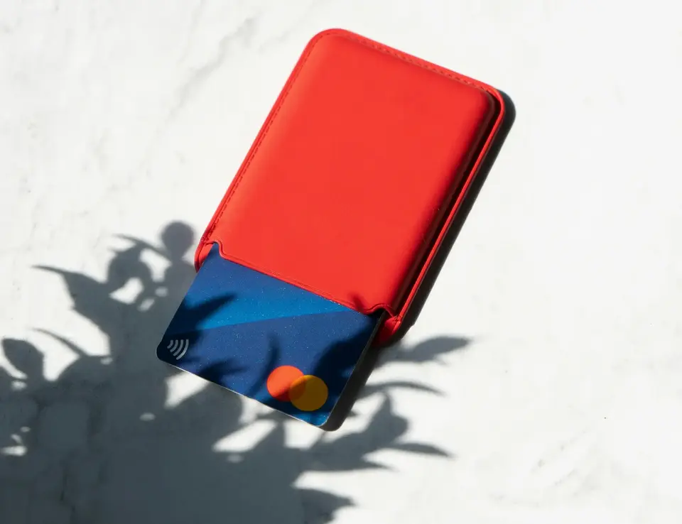 Credit card in a card holder with a shadow of a plant falling on its bottom left corner