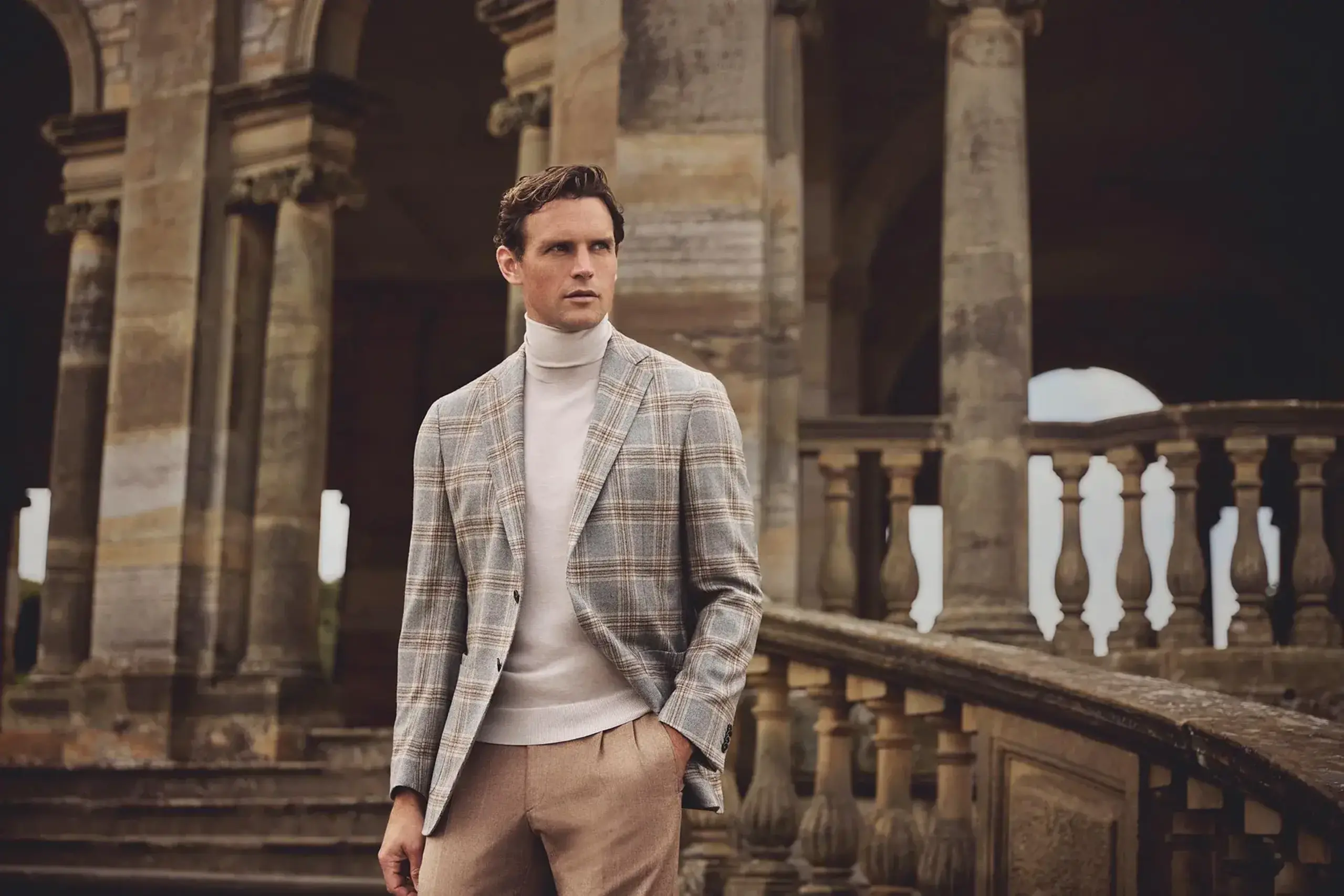 a man in a suit standing in front of a stone building