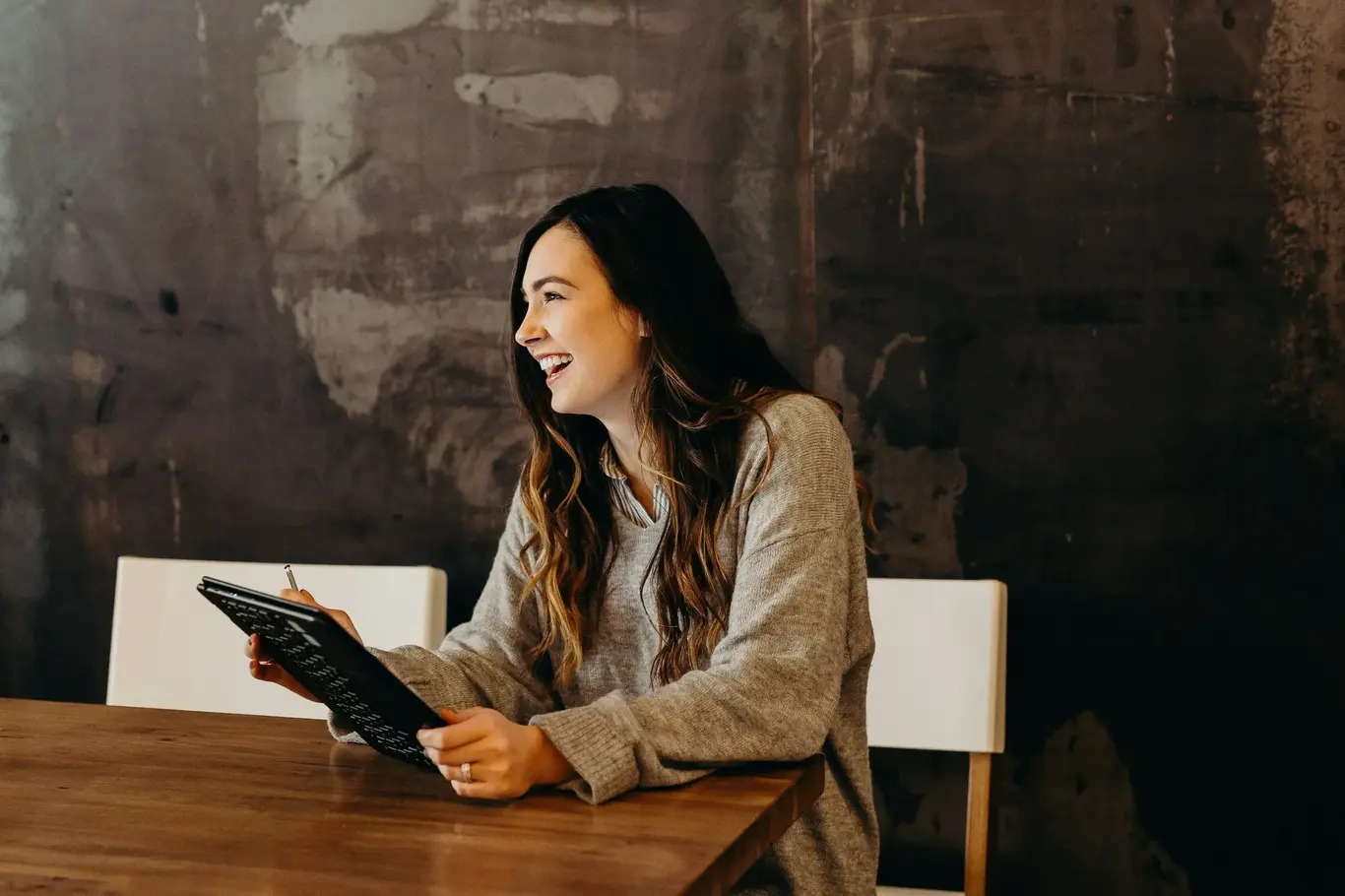 a woman sitting at a table with a tablet