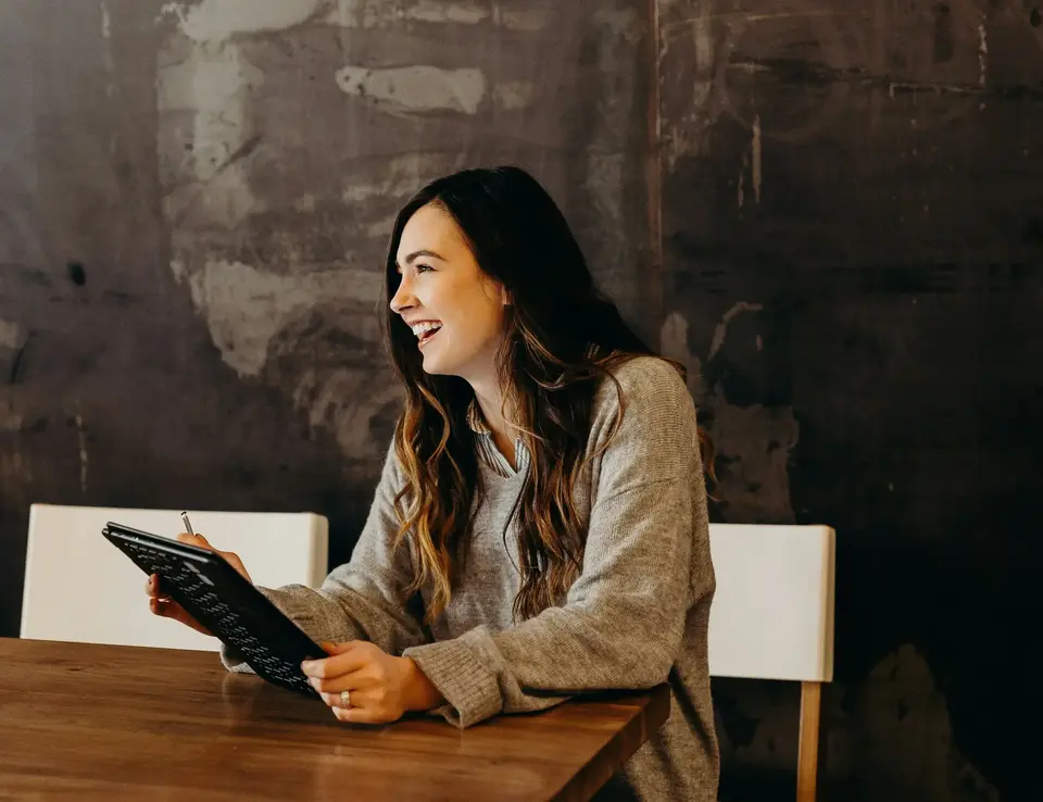 a woman sitting at a table with a tablet