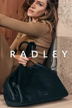 a woman leaning against a wall with a bag