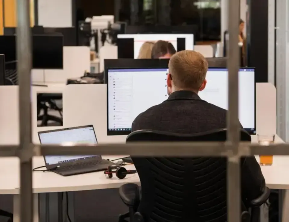 a man sitting at a desk with a few computers behind him