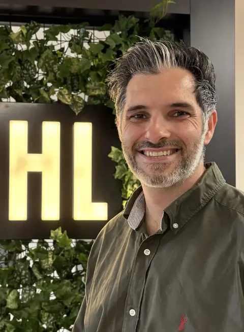 New IDHL member, Alex Wright, standing in the IDHL Leeds office