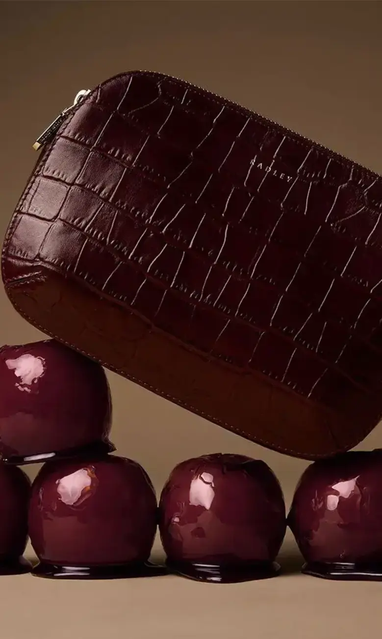 a purse on top of a pile of shiny apples