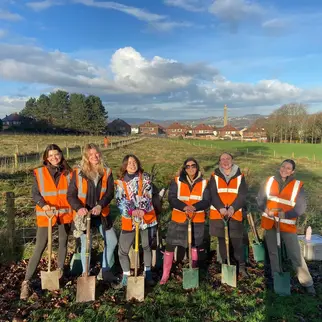 IDHL employees smiling with shovels in a garden