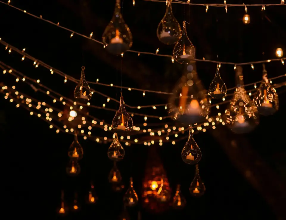 Glass lanterns with fire safe candles glowing outdoors in a dark back garden