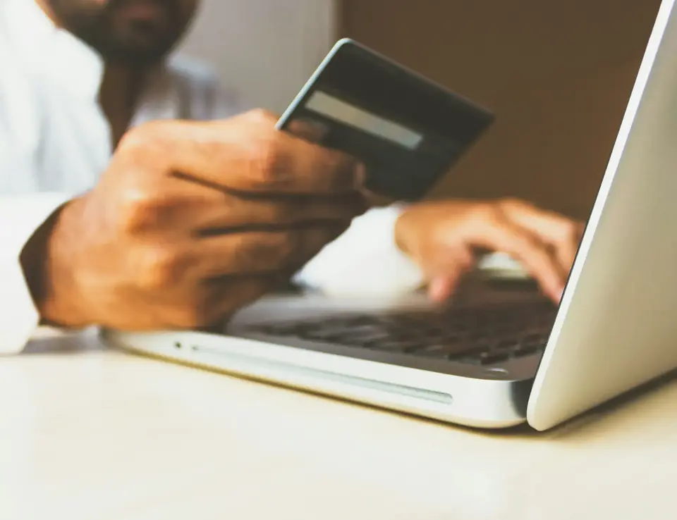 a person holding a credit card and typing on a laptop