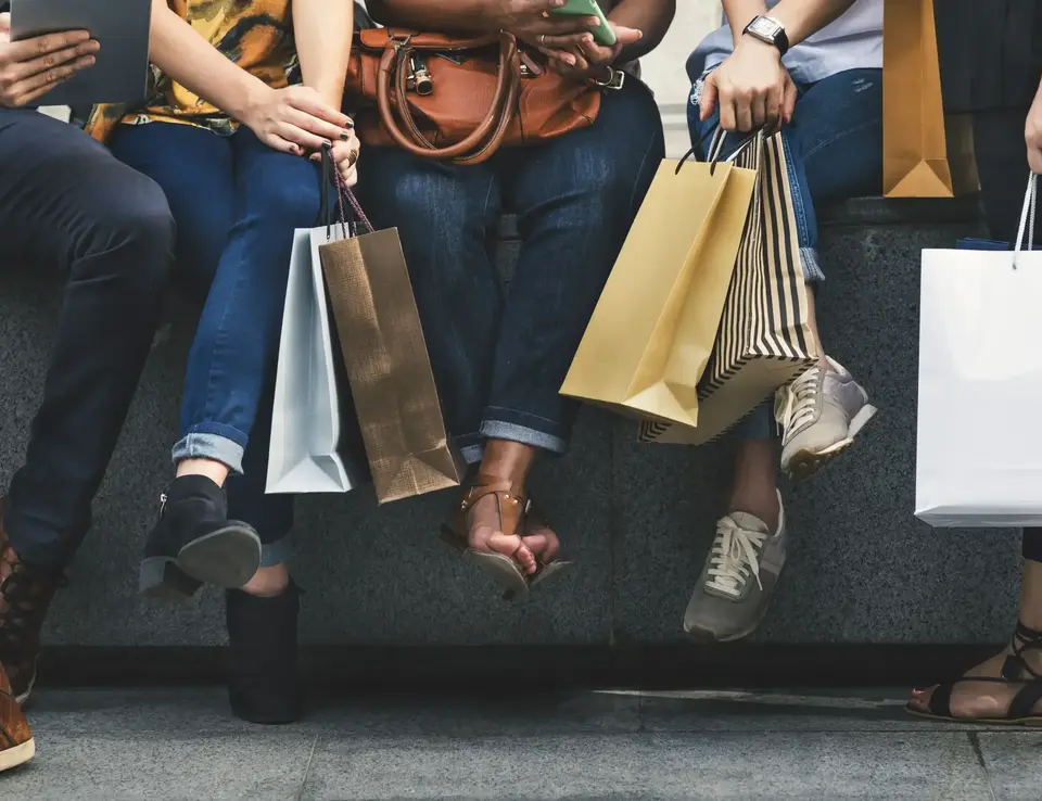 a group of people sitting on a bench holding shopping bags