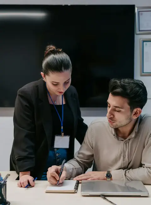 a man and woman looking at a notebook