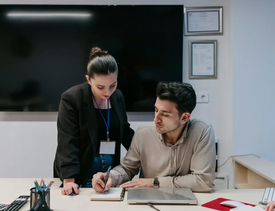 a man and woman looking at a notebook