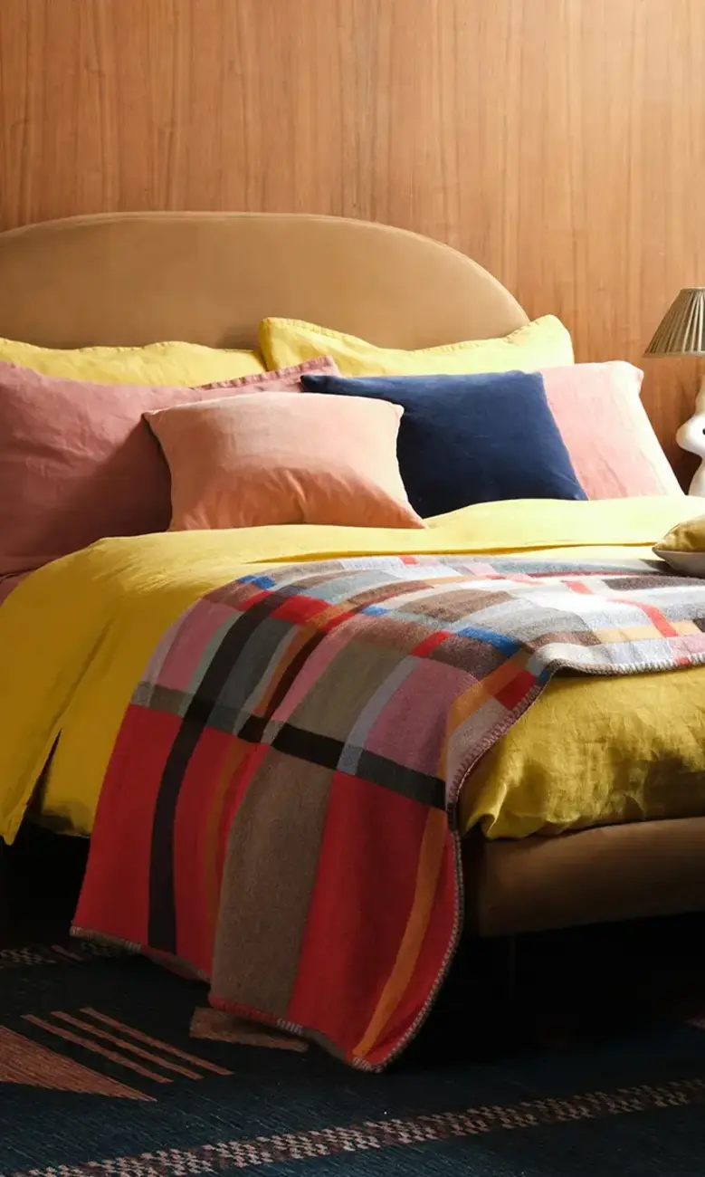 a bed with a yellow blanket and a yellow ottoman