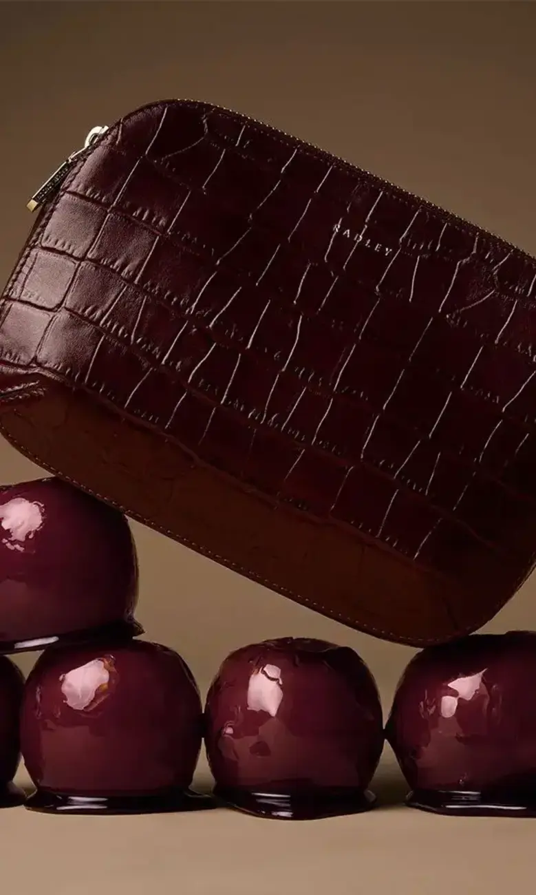 a purse on top of a pile of shiny apples