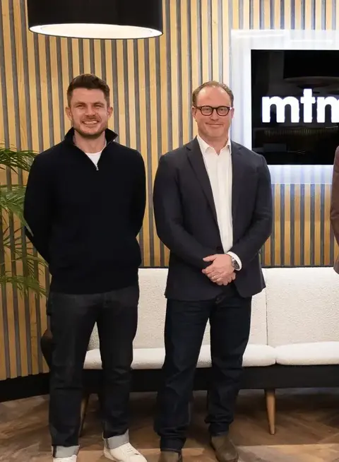 a group of men standing in front of a white couch